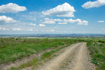 Obraz premium Rocky road thru roamanian hill side landscape with blue sky and fluffy clouds