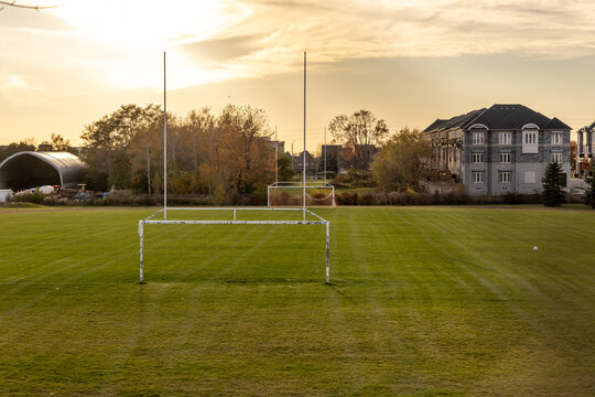 Golden-hour lighting over serene soccer field - goalposts standing tall - suburban houses, trees backdrop. Taken in Toronto, Canada.