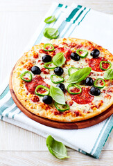 Pizza with salami, jalapeno pepper and black olives. Home made food. Concept for a tasty and hearty meal. Close up.