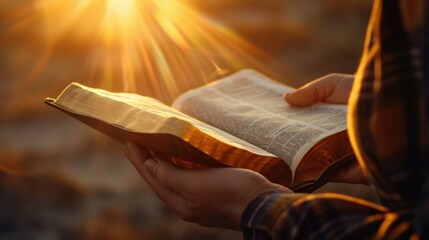 hands hold an open Bible, the sun's rays fall on the Bible.