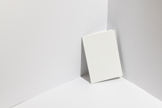A blank canvas rests on a white surface against a corner, with copy space