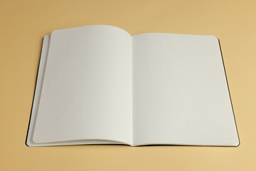 An open blank notebook lies on a beige surface, with copy space