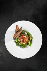 Tuna Tartare with Arugula and Toasts on White Plate - Black Background