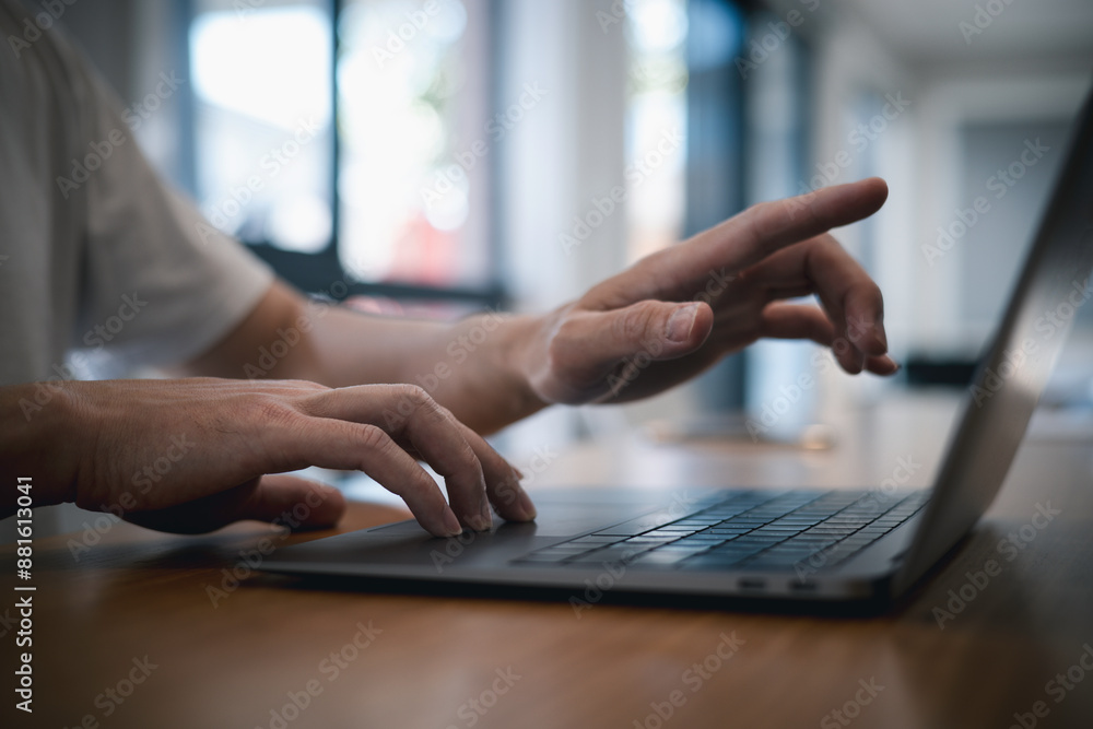 Poster man in casual ware working on laptop computer on office table..