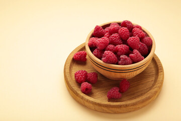 Raspberries in wooden bowl on beige background. Top view