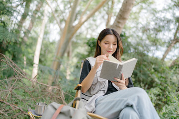 Asian girl sit on a camping chair, reading a book, relax on a relaxing day with nature