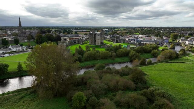 Trim Castle, County Meath, Ireland, October 2023. Drone orbits clockwise into a panoramic view of Fortress ruins and river Boyne under overcast sky on beautiful day.