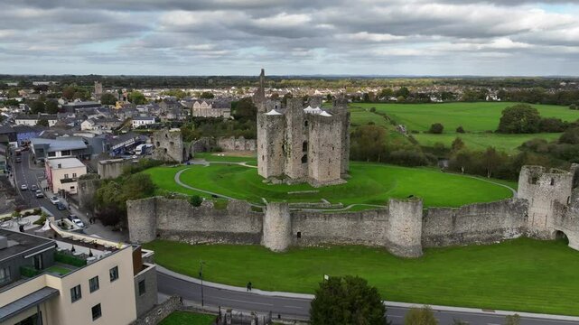 Trim Castle, County Meath, Ireland, October 2023. Drone orbits the Medieval Stronghold counter clockwise around the grassy hillside between river Boyne and town.
