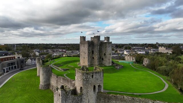 Trim Castle, County Meath, Ireland, October 2023. Drone orbital ascent counter clockwise  of stunning Medieval Stronghold on cloudy day, historic walls and towers in countryside.