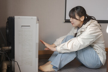 ストーブの前で手をかざす若い女性