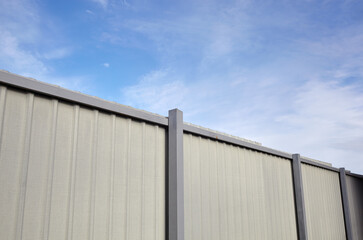 Fototapeta premium Corrugated steel fence against blue sky. Corrugated metal texture surface or galvanize steel