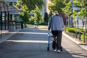elder man walking outdoors with walker rollator