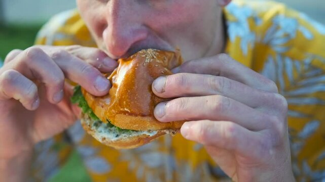 Fresh burger ,close up in hands hangry man open mouth eating junk tasty meal from fast food. Soft focus. 
