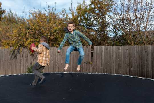 boys jumping and running on trampoline on sunny fall day