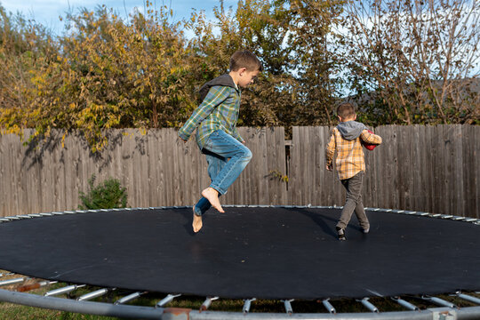 children jumping and playing on trampoline on a fall day