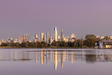 Melbourne skyline reflected in Albert Park Lake with purple sunrise