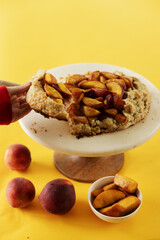 child's hand serving a slice of peach galette on a yellow background