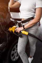 A woman fills a car with fuel at a gas station. Gas station service. Refueling concept. 