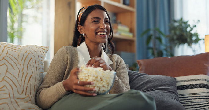 Smile, girl and relax on sofa with popcorn for watching movies, streaming comedy film and unwind on weekend for break. Woman, laughing and snack in home for online subscription and entertainment. - Powered by Adobe