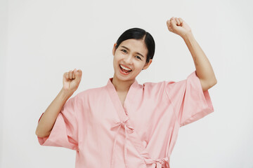 A young Asian female wearing a pink patient uniform stands isolated against a white wall...