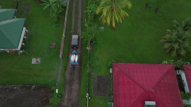 Jeep driving boat on trailer surf boards sunrise early morning Teahupoo Tahiti French Polynesia aerial drone birdseye pan end of the road Olympic venue village town buildings island coastline