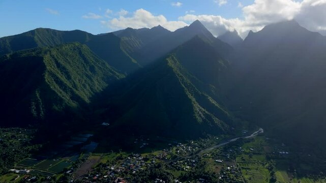Teahupoo Tahiti village afternoon aerial drone view French Polynesia bay coastline blue sky clouds WSL Surfing summer Olympic venue town village mountain peaks surfer wave reef forward down motion