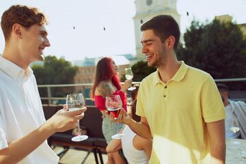 Friends gather for sunny celebration, raising their glasses in toast to happiness of moment. Outdoor party. Concept of party, Friday mood, celebration, summer holidays, relax.
