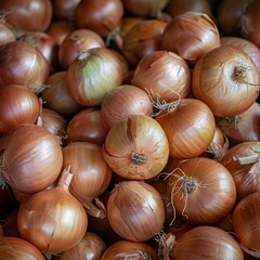 A large pile of fresh brown onions is displayed, showcasing their natural texture and colors. The onions have a golden-brown hue with varying shades and imperfections, highlighting their organic natur