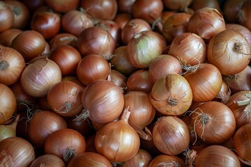 A large pile of fresh brown onions is displayed, showcasing their natural texture and colors. The onions have a golden-brown hue with varying shades and imperfections, highlighting their organic natur