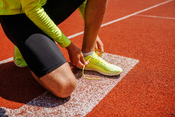 Athlete tying running shoe on track