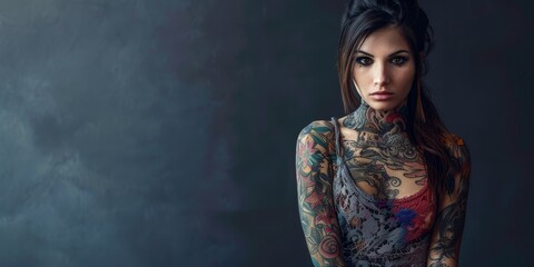 Fototapeta premium A woman with tattoos on her arms and neck stands in front of a grey wall