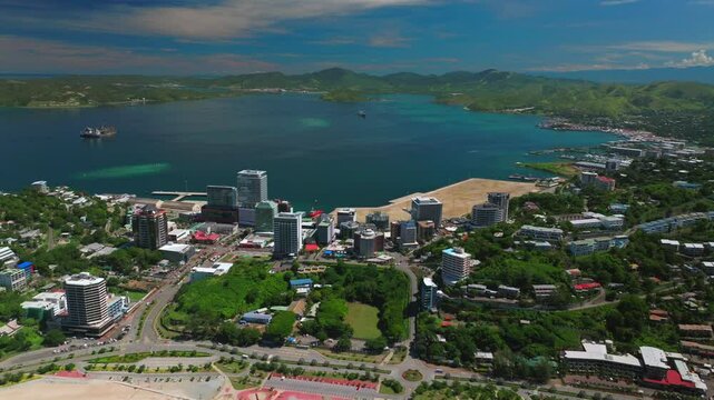 Beautiful sunny blue sky morning Ela Beach Port Moresby Harbour Marina Papua New Guinea aerial drone car traffic PNG Crown Hotel Plaza Hilton Walter Bay Coral Sea capital city backwards pan up