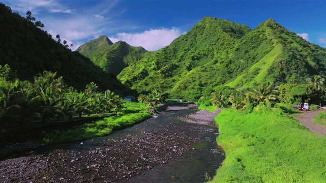 Mountain valley river coconut trees Teahupoo Tahiti aerial drone French Polynesia South Pacific island bright afternoon sunny green lush blue sky clouds WSL surfing Olympic venue end of road backwards