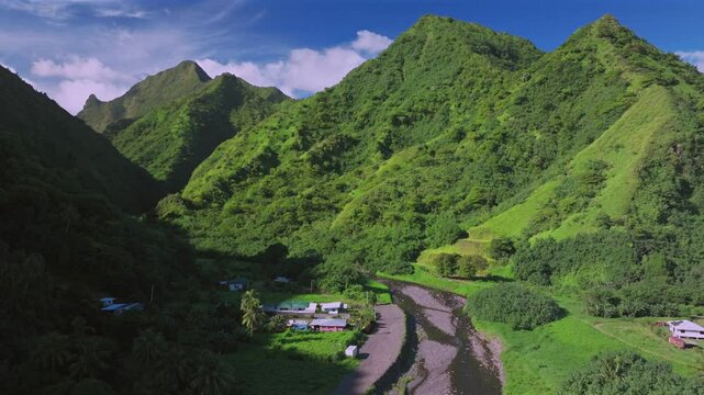Towering mountains valley river Teahupoo Tahiti aerial drone French Polynesia South Pacific island volcano bright morning afternoon sunny green lush bluesky WSL surfing Olympic venue forward up reveal