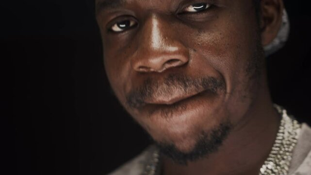Closeup of Black male rapper singing and dancing at camera on black background