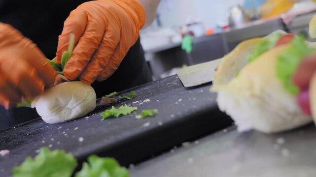 A close-up view of hands preparing small mortadella sandwiches for a party. The scene captures the detailed process of assembling these delicious snacks for a festive occasion.