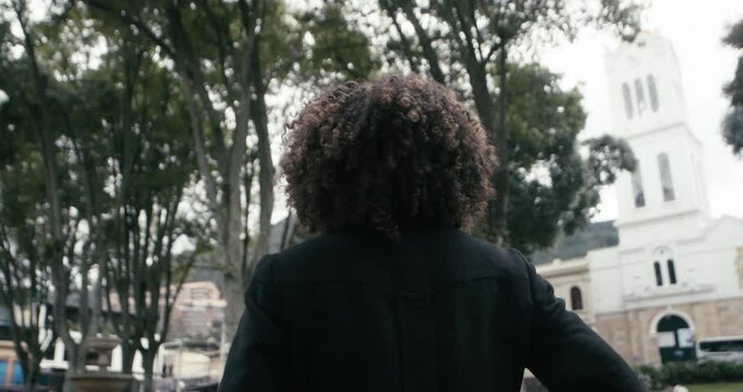 B roll shot of woman in a suit with curly hair walks looking around in the city of Bogota, Colombia