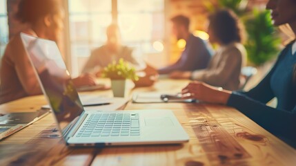 A business meeting is taking place around a wooden table in a modern office environment.