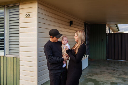 Young Australian family with baby boy together outside weatherboard  home in winter