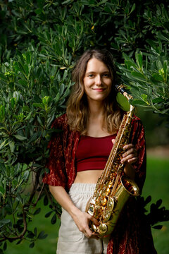 Woman holding saxophone in a lush garden