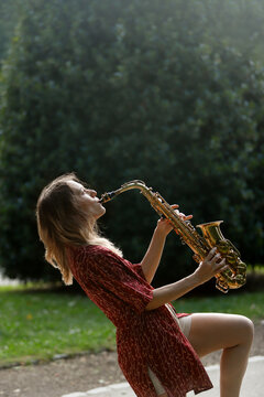 Woman playing saxophone in a park with eyes closed
