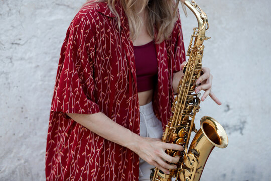 Unrecognizable woman playing a saxophone outdoors with focus on instrument