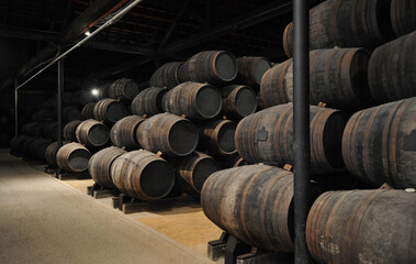 Warehouse with barrels stacked on top of each other. Wine cellar with barrels made of oak wood....