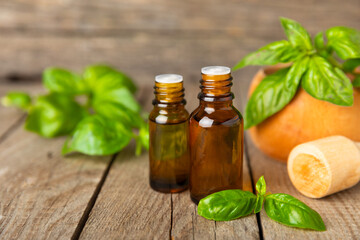 Basil essential oil on a textured wooden background. Basil essential oil and fresh leaves. Aromatherapy. Aroma oil. Medical herbs. Alternative medicine. Place for text. Copy space.