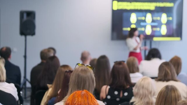 Diverse audience attentively listens to a speaker presenting at a business conference, emphasizing professional engagement and networking.