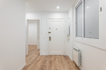 A modern apartment hallway with wooden flooring and white walls, creating a bright and clean space