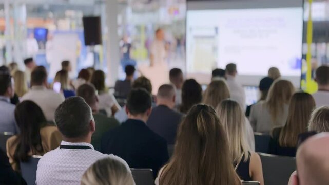 Group of people listening to a presentation during a business seminar or conference in a spacious room.