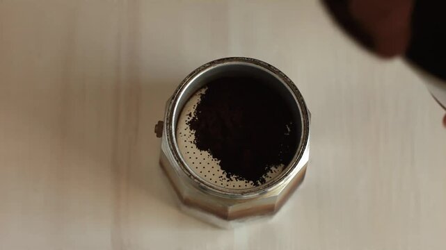 Close-up of a hand pouring coffee into a geyser coffee maker. View from above. 
