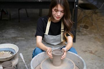 Young women is making earthenware at workshop.