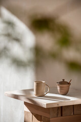 An elegant minimalist concept featuring modern ceramic mugs and cups on a neutral beige wooden table background. Minimalist design.